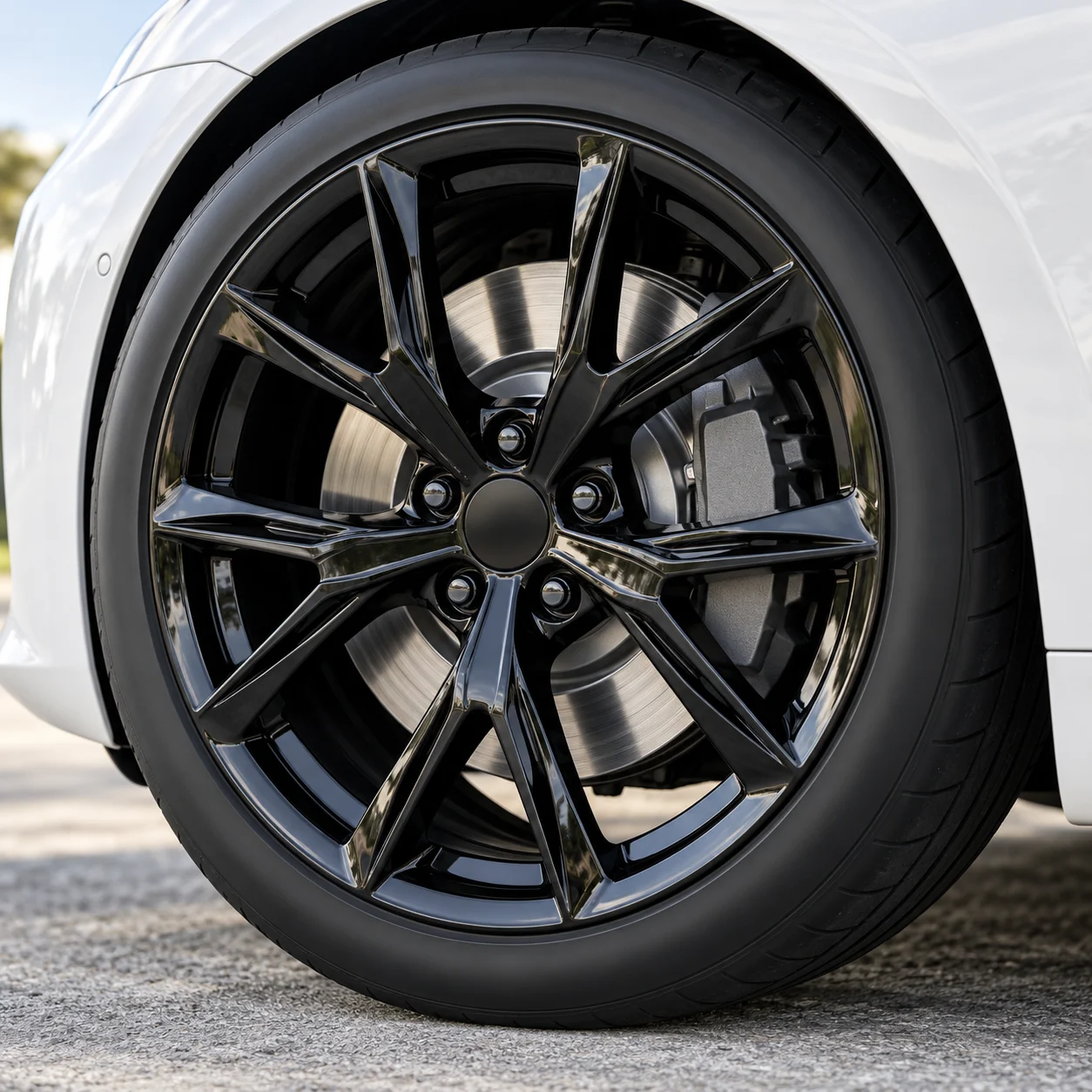 Illustrative close-up of a gloss black clean multi-spoke forged wheel on a white electric sedan
